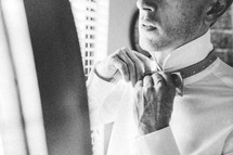 a groom adjusting his bow tie 