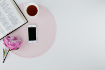 place mat, flower, iPhone, tea cup, and open Bible 