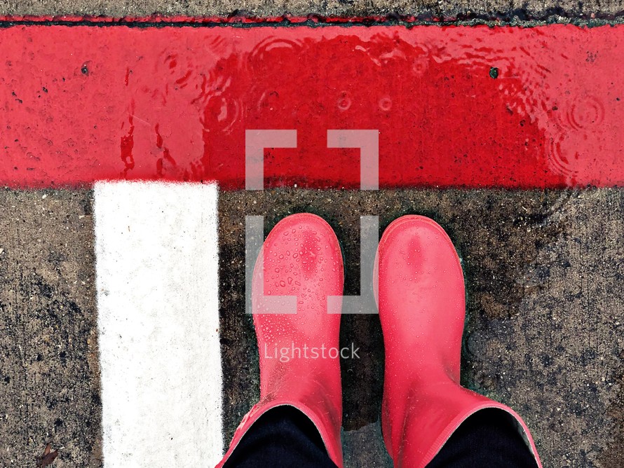 rain boots and wet lines on pavement - looking down at the ground