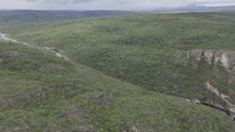 Drone flies over river cutting through valley