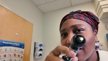 African American woman doctor checking patient eye 