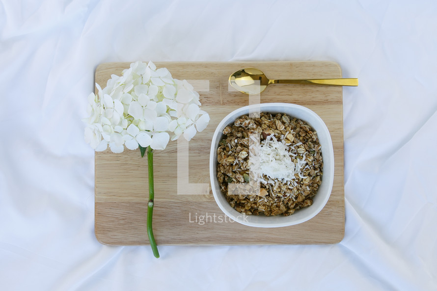 bowl of oatmeal, spoon, and flowers on a wooden tray 
