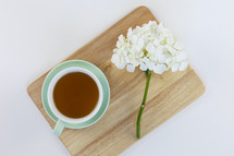cup of tea and flowers on a cutting board 