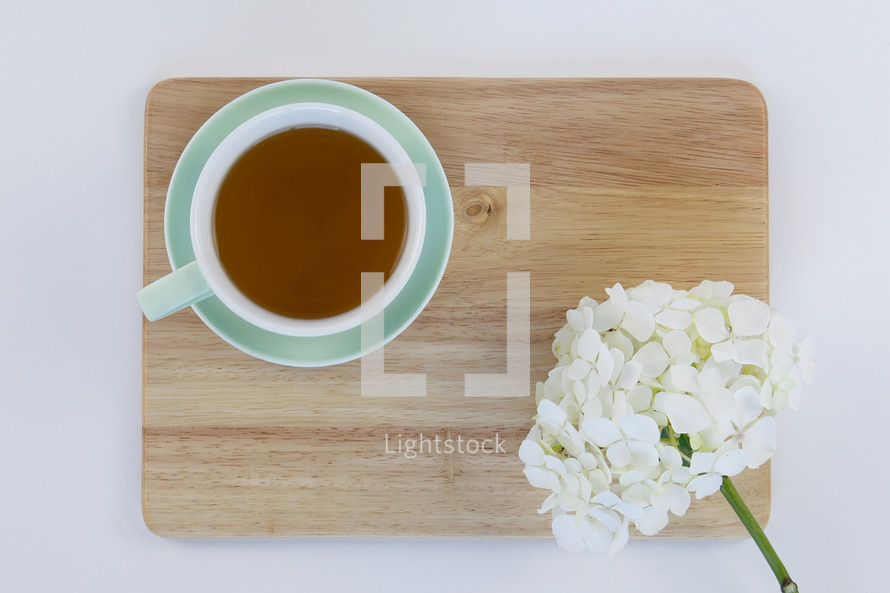wood citing board with flowers, and cup of tea 