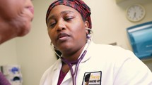 African American woman doctor checking patient heart 