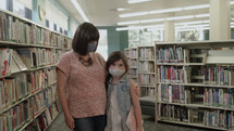 a mother and daughter at the library wearing face masks 