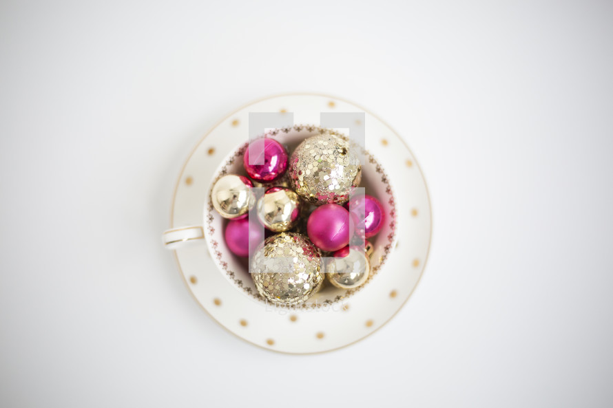 gold and fuchsia ornaments in a tea cup 