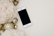 cellphone, gold ornaments and light pink flowers 