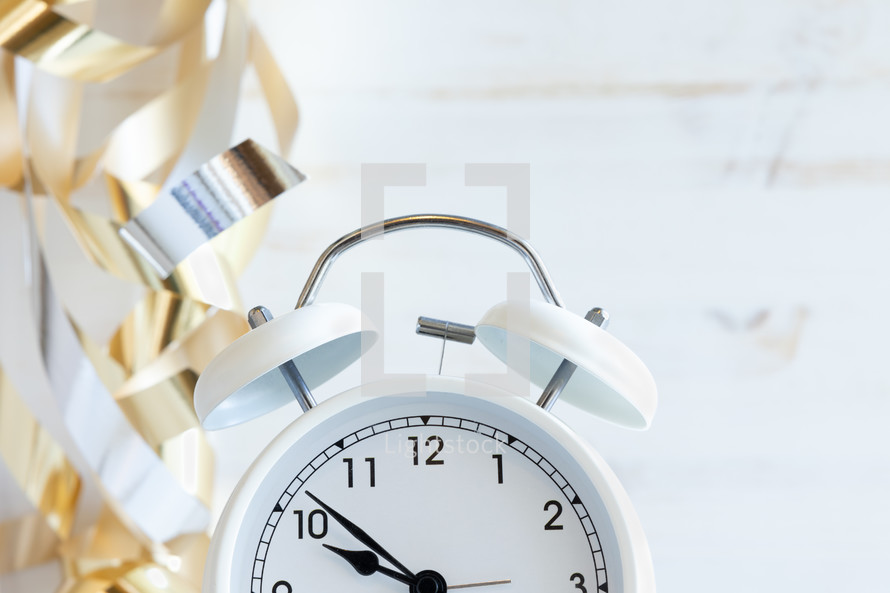 gold streamers and alarm clock on a white background