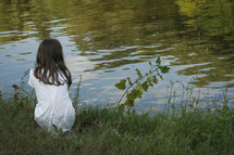 girl looking out at pond water 