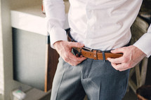 a groom adjusting his belt 