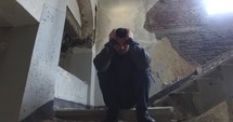 man sitting on steps in an abandoned building 