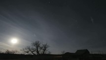 moon and moving clouds over a ranch at night 