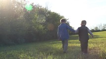 boys walking holding hands in a field outdoors 