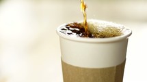 pouring coffee into a paper cup 