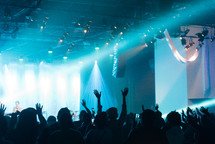 silhouettes of people with hands raised at a concert 