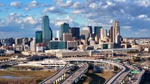 Forward aerial pan shot of downtown Dallas Texas skyline and Interstate 35 below.	