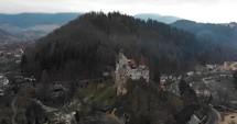 Aerial, drone shot, orbiting around the Bran castle, home of the Dracula legend, on a foggy, overcast, fall day, in Transylvania, Romania
