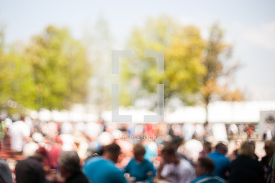 Blurred background photo of a crowd at an event or festival.