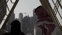 Middle eastern man and woman, married couple in Dubai looking at Burj Khalifa and skyscrapers at Dubai mall.