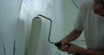 Woman painting wall with paint roller - close up shot