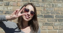 Young hippy woman shows peace and love sign with hands - close up