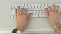 Stylish woman types on keyboard and uses mutlitouch trackpad on computer