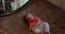 Infant girl laying down on chair in living room alone