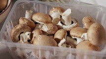 A Lady's Hand is Retrieving Mushrooms From the Food Container - Close Up