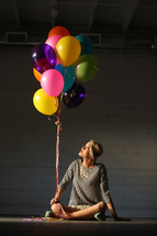 a young woman sitting on the floor with balloons 