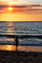 a boy running on a beach at sunset 