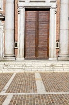 old wood doors and brick pavers near an old church in Italy 