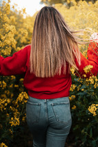 Spring fashion, woman walking through yellow flowers rapeseed field