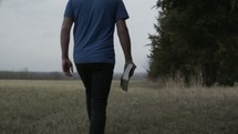 a man walking carrying a Bible 