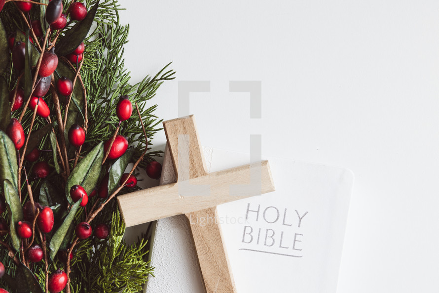 Bible, cross, and branch with red berries on a white background