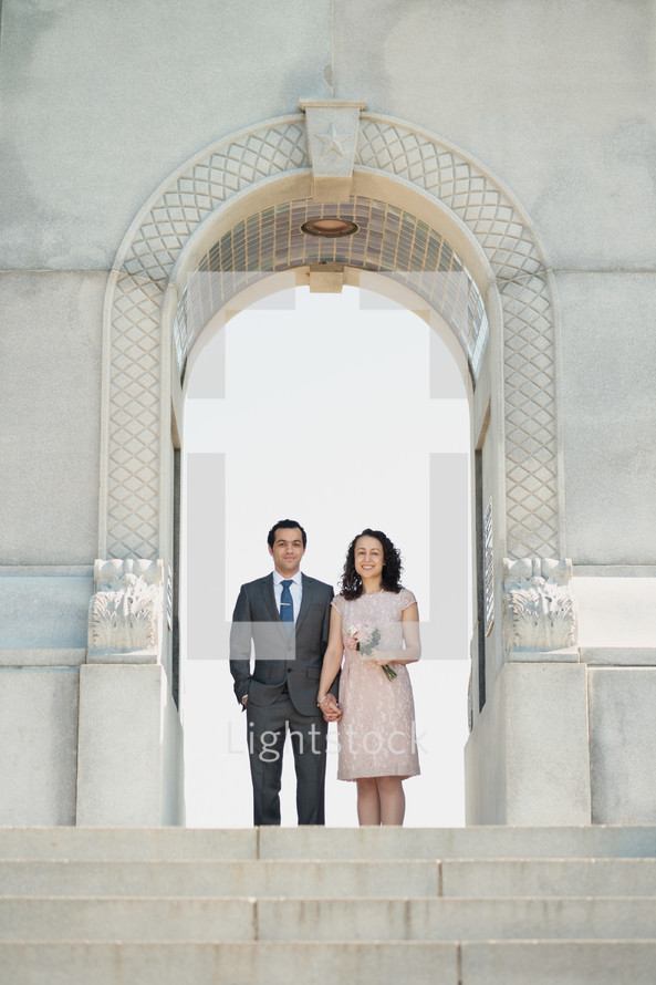 portrait of a bride and groom standing under an arch 