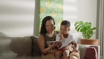 Latina mother and son at home playing on a tablet