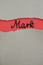 Mark - torn open kraft paper over light red paper with the name of the Gospel of Mark