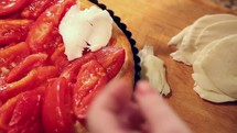 Cheese being placed on a tomato pizza.