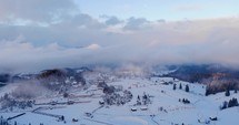 Scenic View Of A Snowy Village Background With Cloudy Sky During Winter in Fundata, Brasov- Aerial Shot