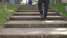 a blind man using a walking stick to walk up steps 