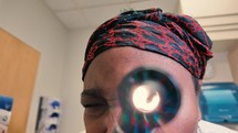African American woman doctor checking patient eye 