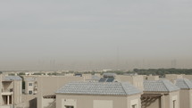 Houses and rooftops in Dubai with distant city skyline - buildings, Burj Khalifa in distance as sand and dust cloud covers city.