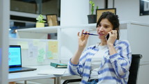 Young Female Manager Calling on Mobile Phone at Office Cubicle
