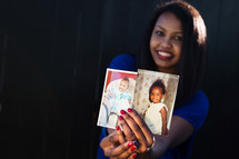 African American mother holding up photos of her children 