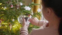 A Girl is Turning the Key of the Christmas Globe - Close Up