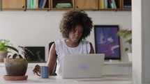 Happy Black Businesswoman Using Computer in Modern Office with Colleagues. Stylish Beautiful Manager Smiling, Working on Financial and Marketing Projects. Drinking Tea or Coffee from a Mug.
