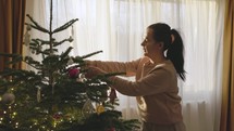 A Girl is Arranging the Hanging Decorations on the Christmas Tree - Medium Close Up