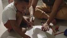 Latina mother and son spending time together coloring on the floor