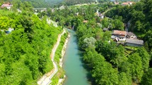 Aerial shot drone hovers over river lined by green trees